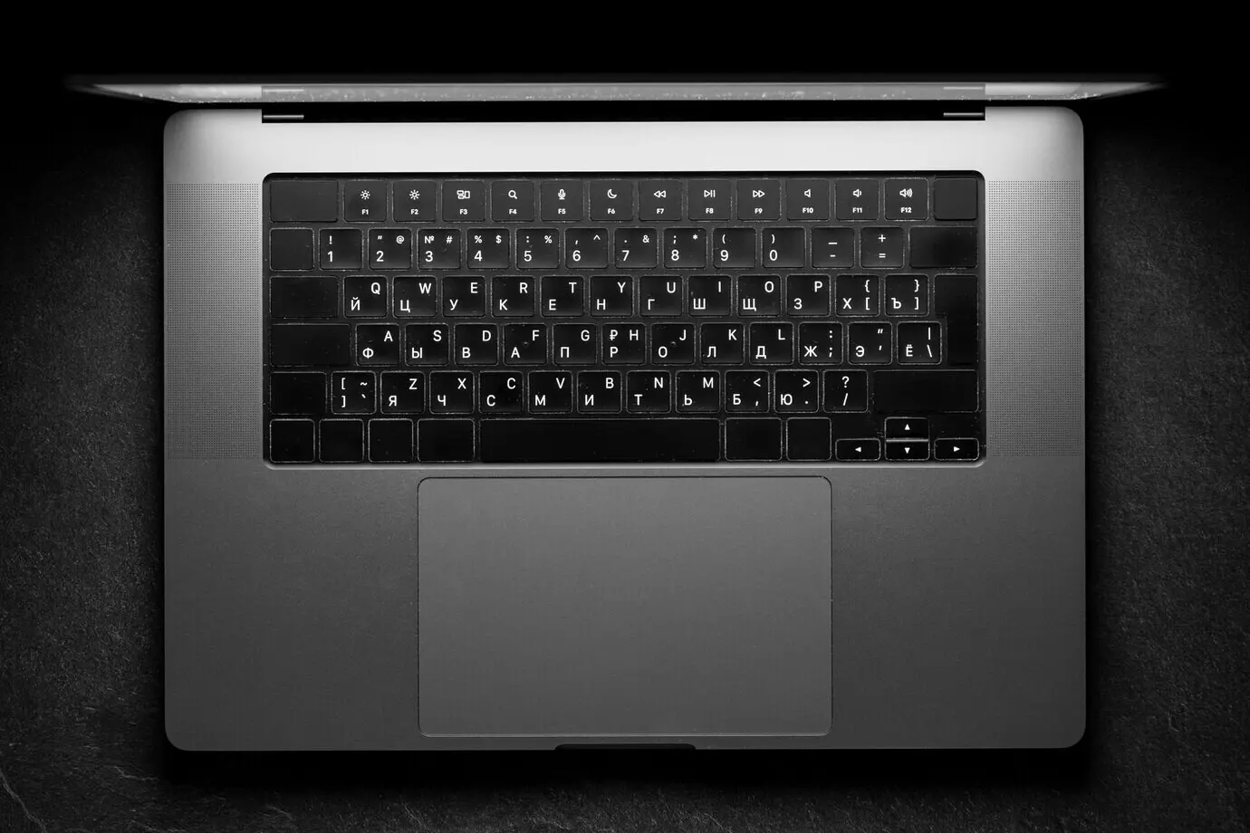 Minimalistischer Laptop in einem schwarz-weißen Arbeitsbereich vor ruhigem technischen Hintergrund.